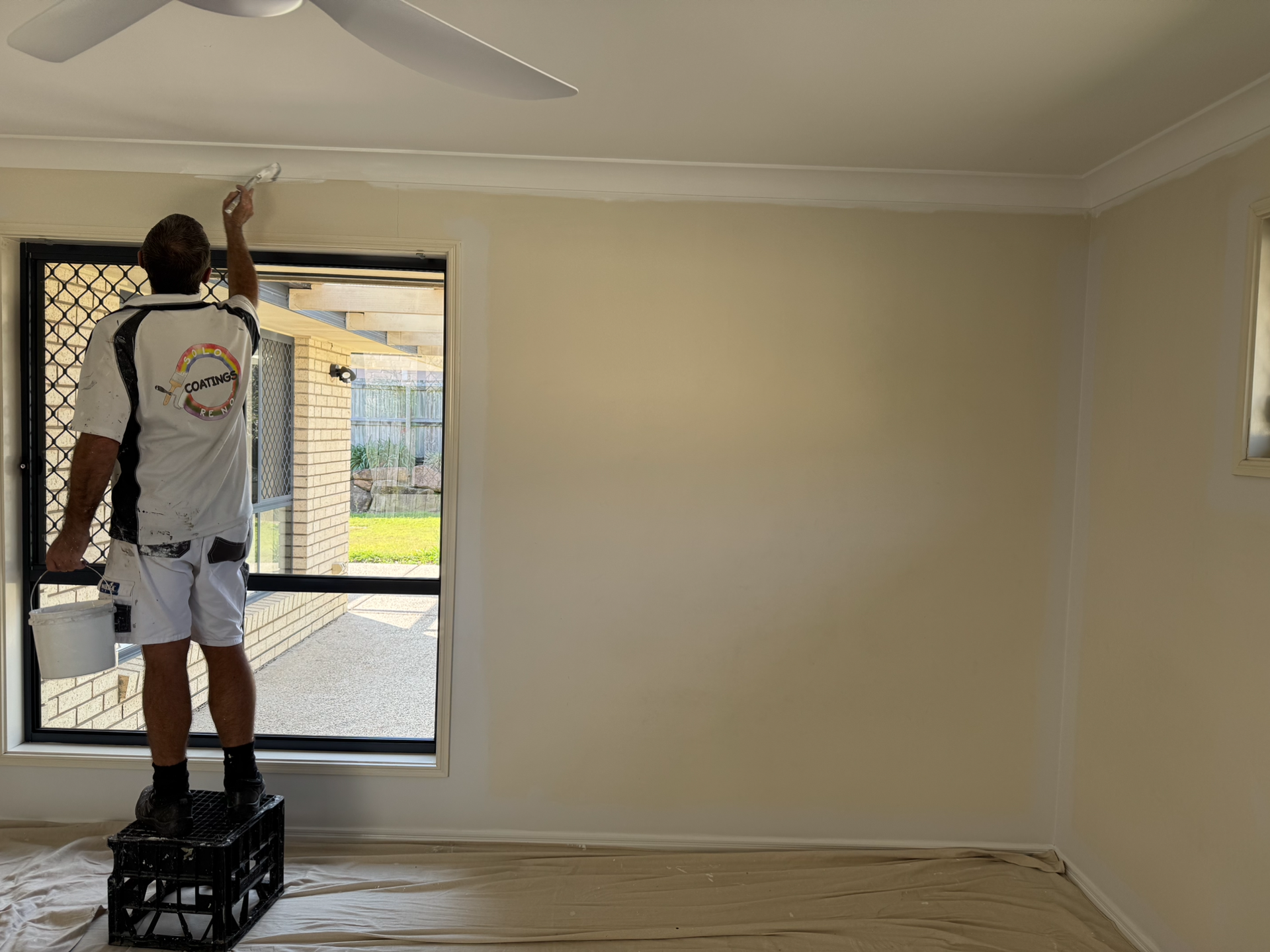 A Man Painting A Wall Standing In Front Of A Glass Door— Solo Reno Coatings In Gold Coast, QLD