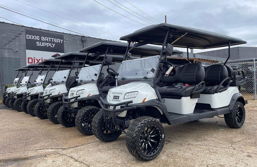 A row of golf carts are parked in front of a building.