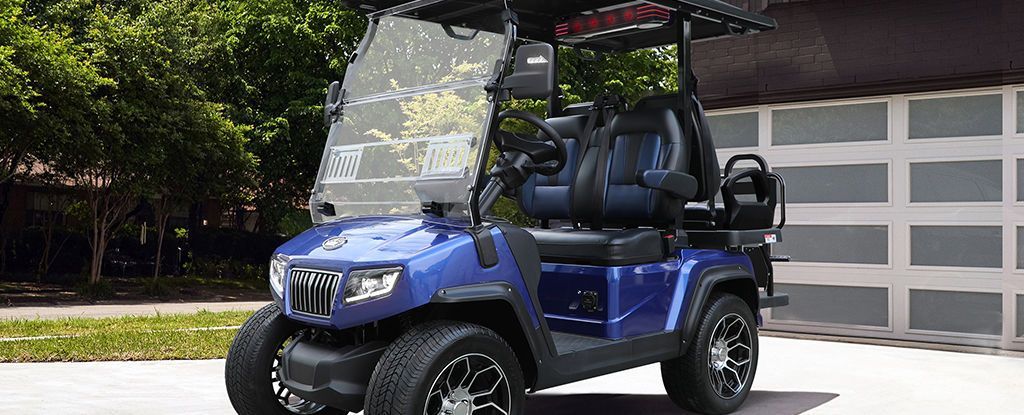 A blue golf cart is parked in front of a garage door.