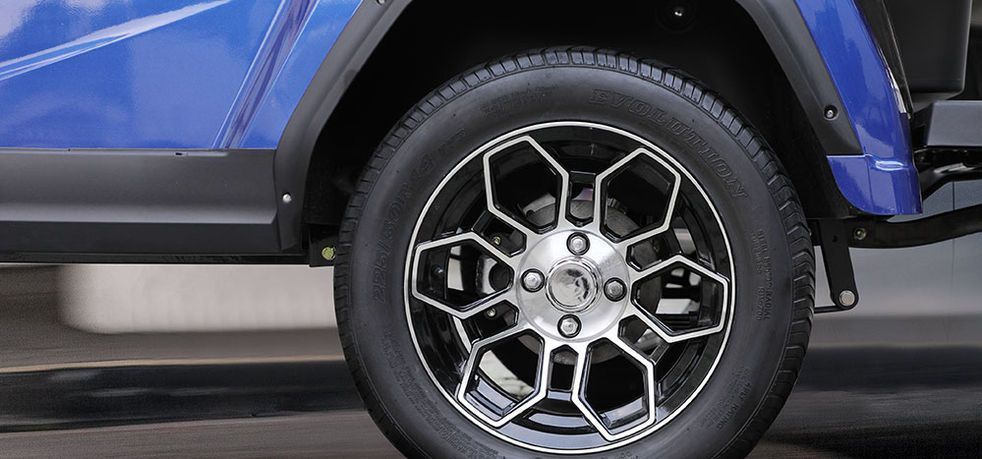 A close up of a blue golf cart wheel and tire.