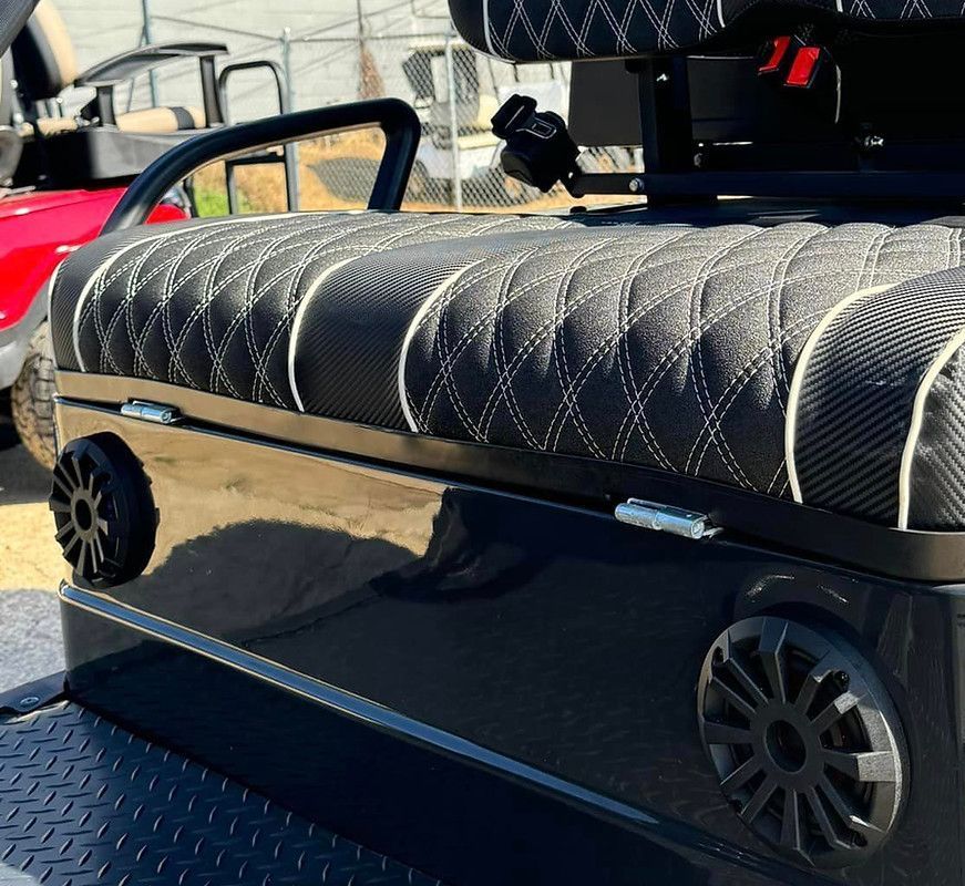 A black golf cart with speakers on the back