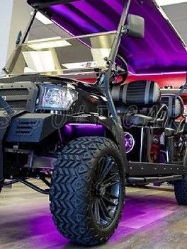 A golf cart with purple lights on it is parked in a room.