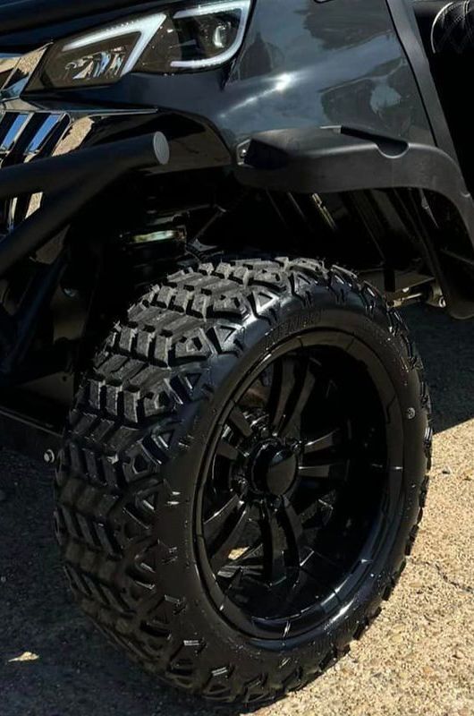 A close up of a black golf cart with black wheels and tires.
