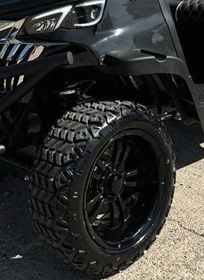 A golf cart with black wheels and tires is parked on the side of the road.