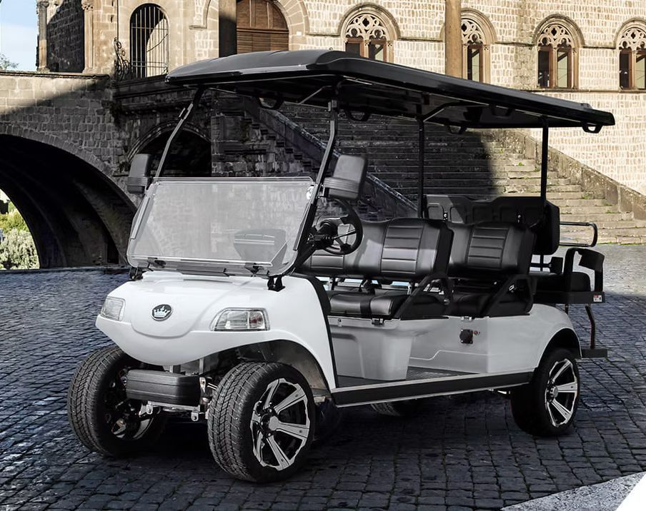 A white golf cart is parked on a cobblestone street in front of a castle.