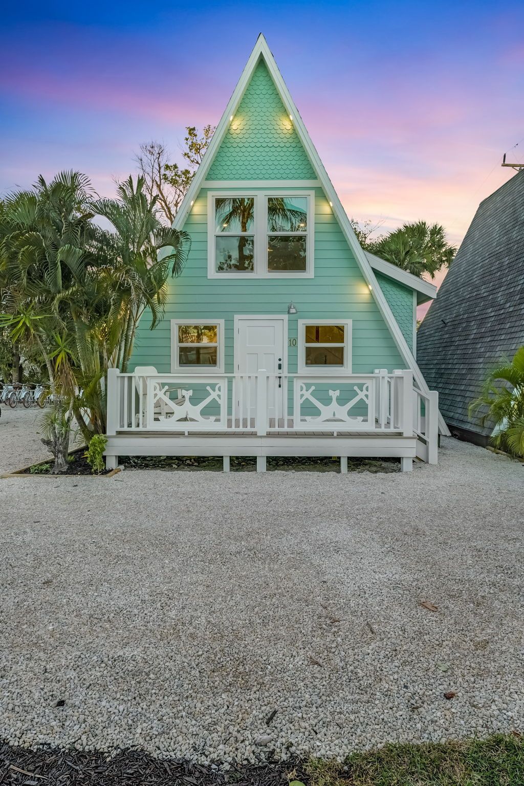 A woman is standing in front of a yellow a frame house.
