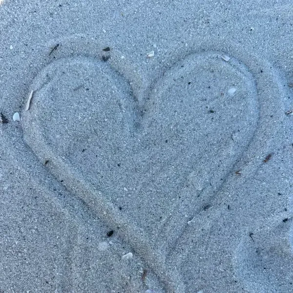 A heart is drawn in the sand on the beach.