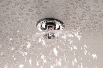 Fire sprinkler head spraying water onto a ceiling.