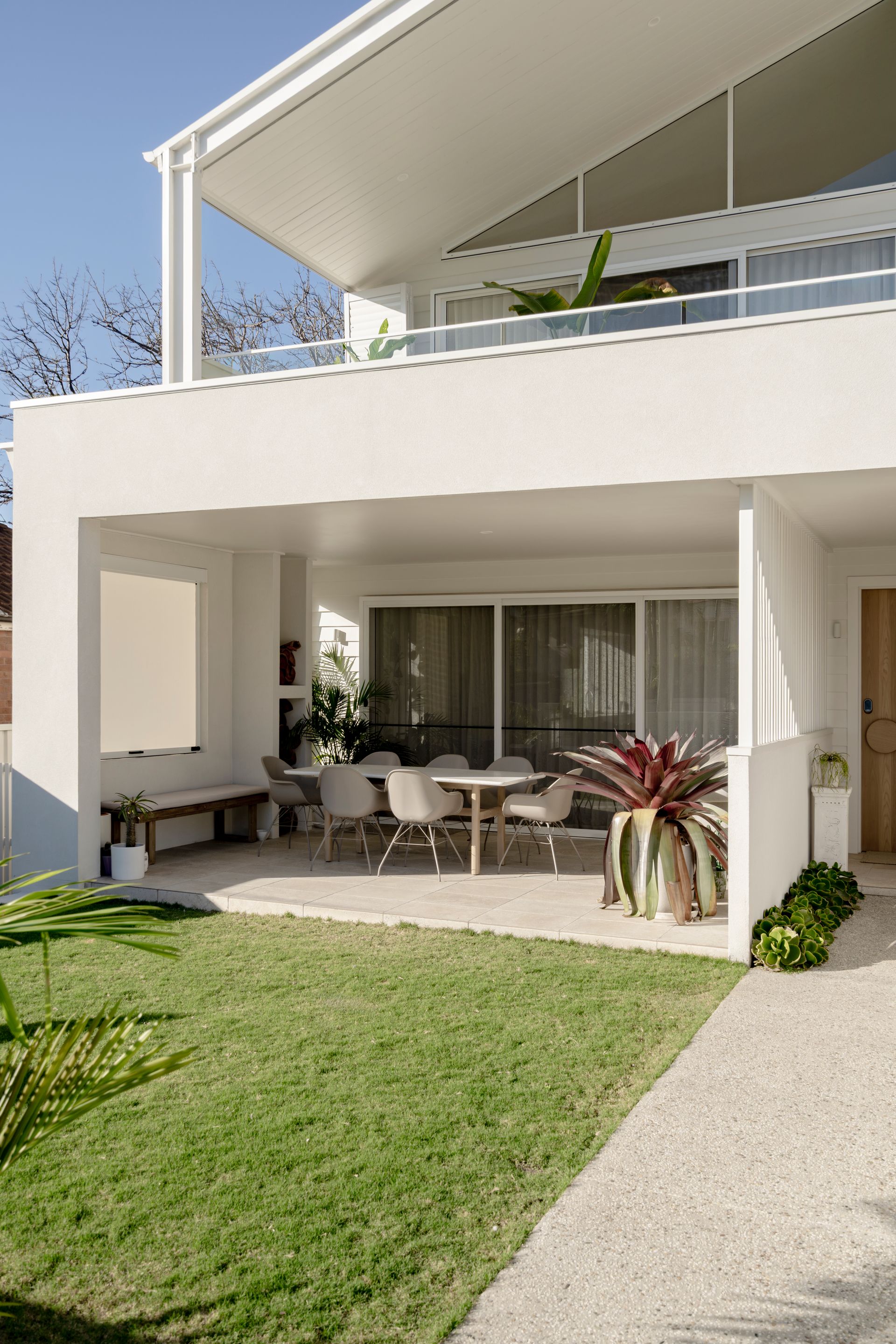 A white house with a patio and a table and chairs on it — DeBu Studios In Southern Sydney, NSW