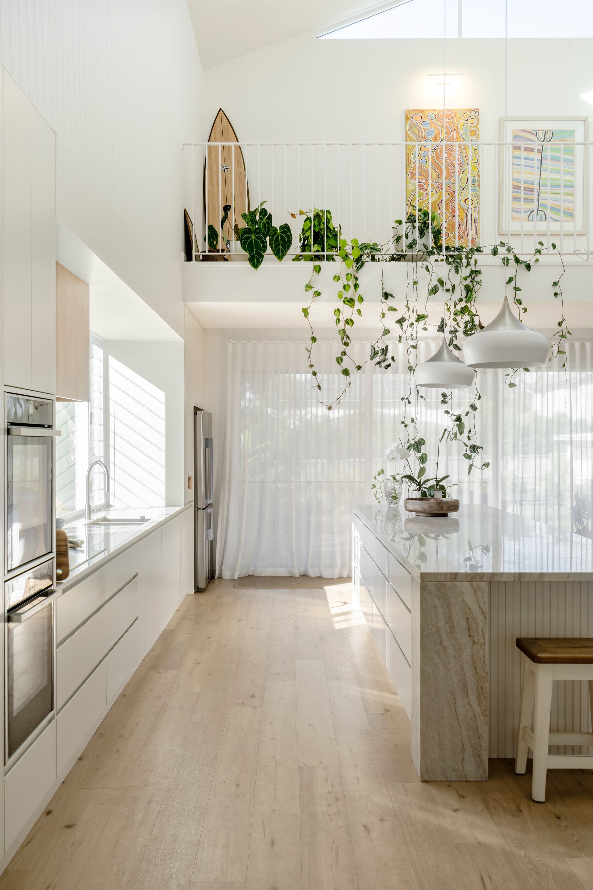 A kitchen with white cabinets, a large island, and a balcony — DeBu Studios In Southern Sydney, NSW