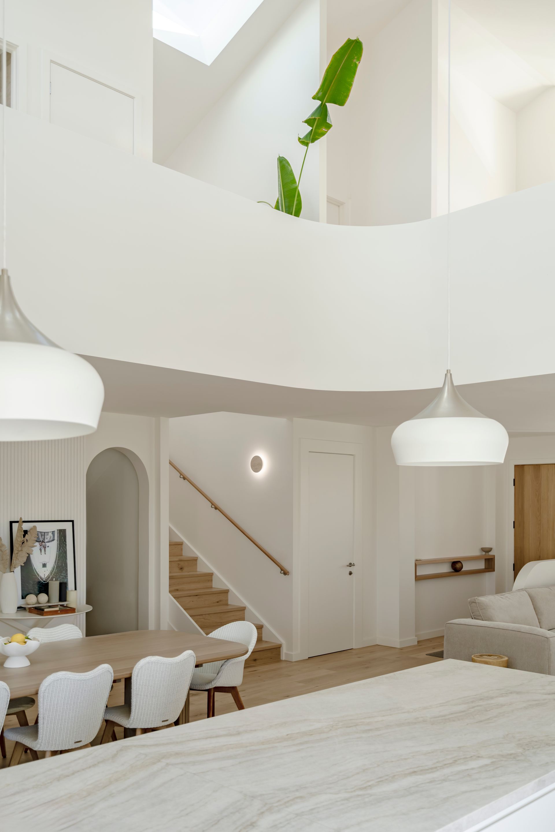 A living room with a table and chairs and a staircase — DeBu Studios In Southern Sydney, NSW