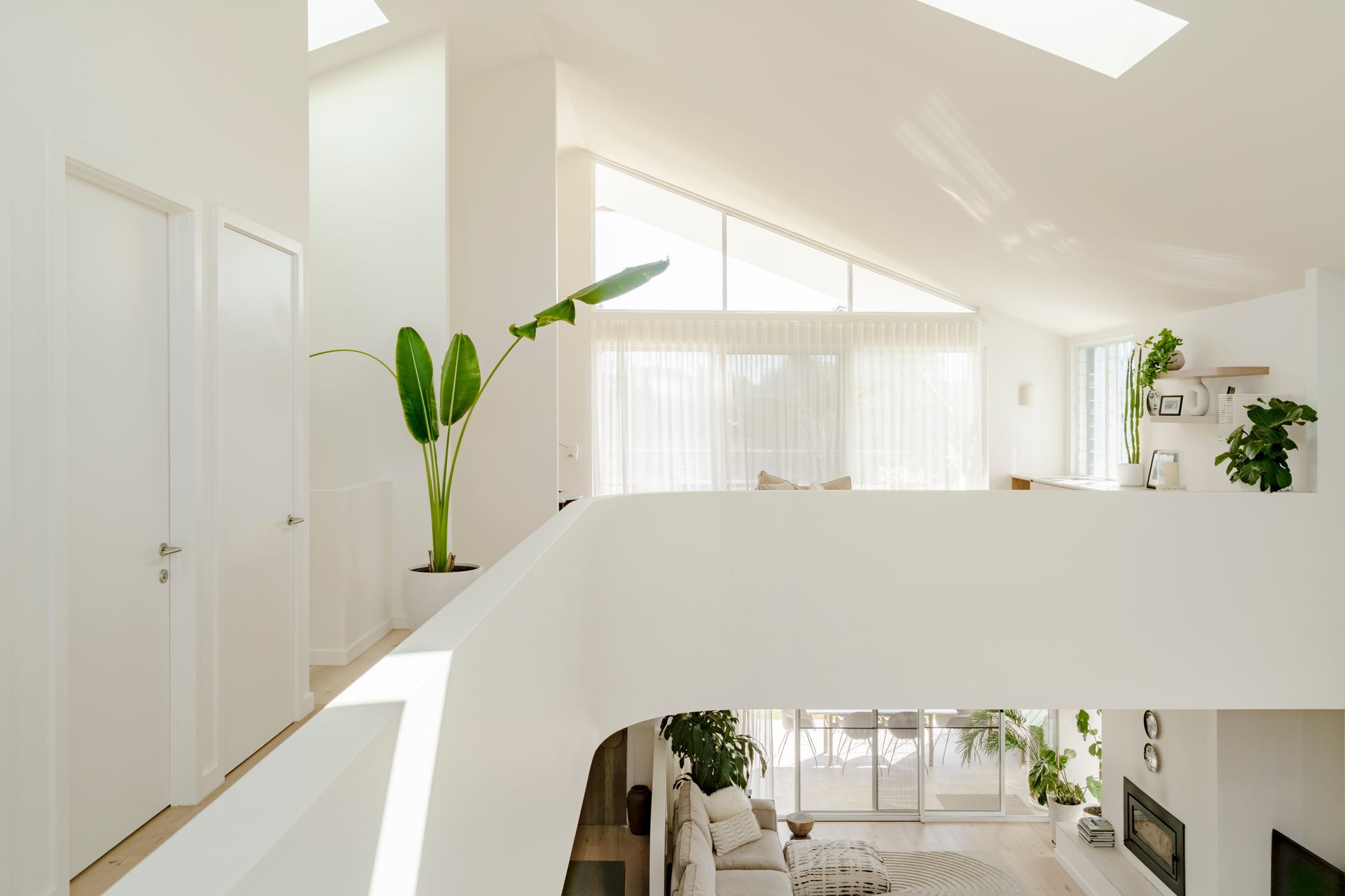 A view of a living room from the second floor of a white house — DeBu Studios In Southern Sydney, NSW