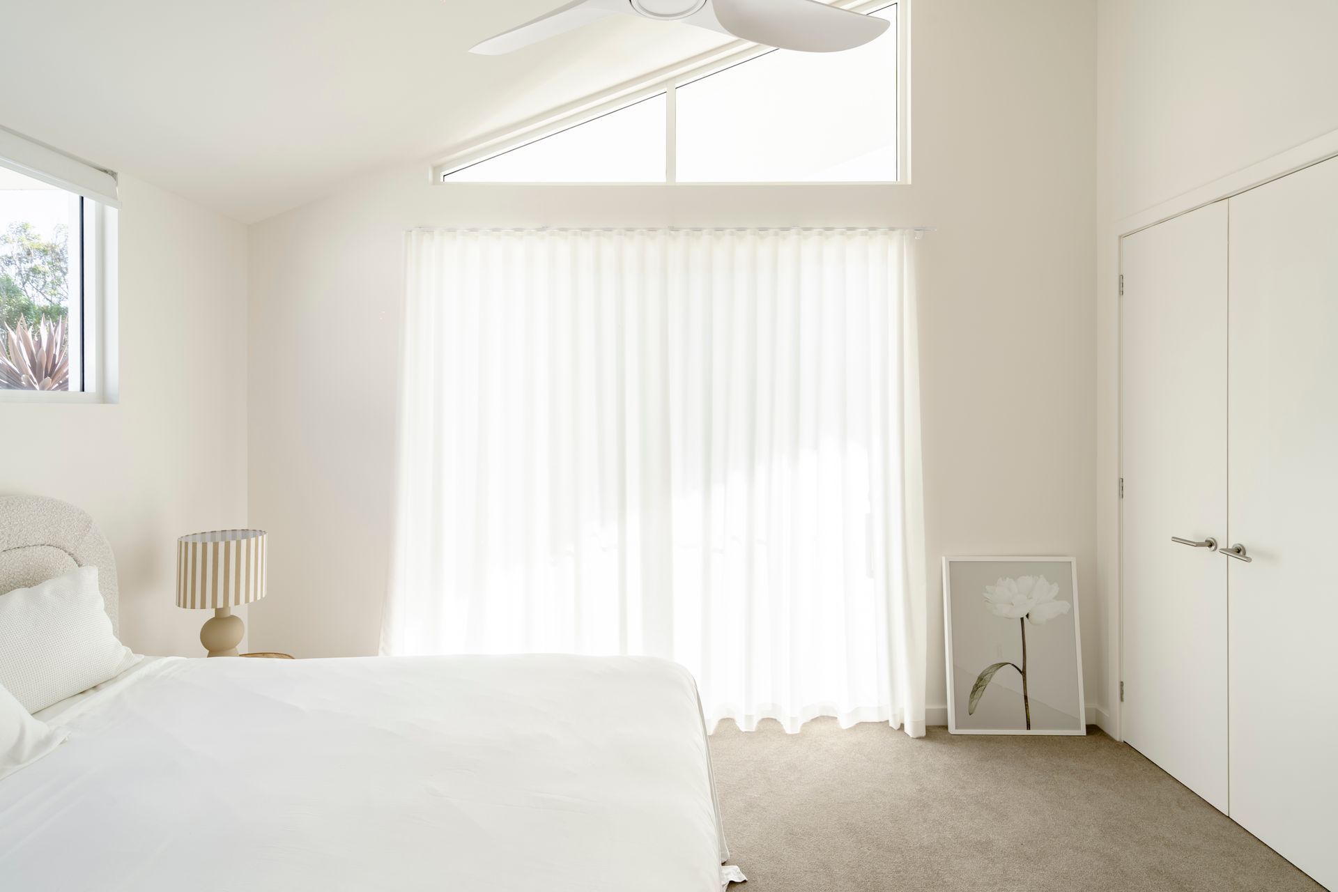 A bedroom with a bed, lamp, and sliding glass doors — DeBu Studios In Southern Sydney, NSW