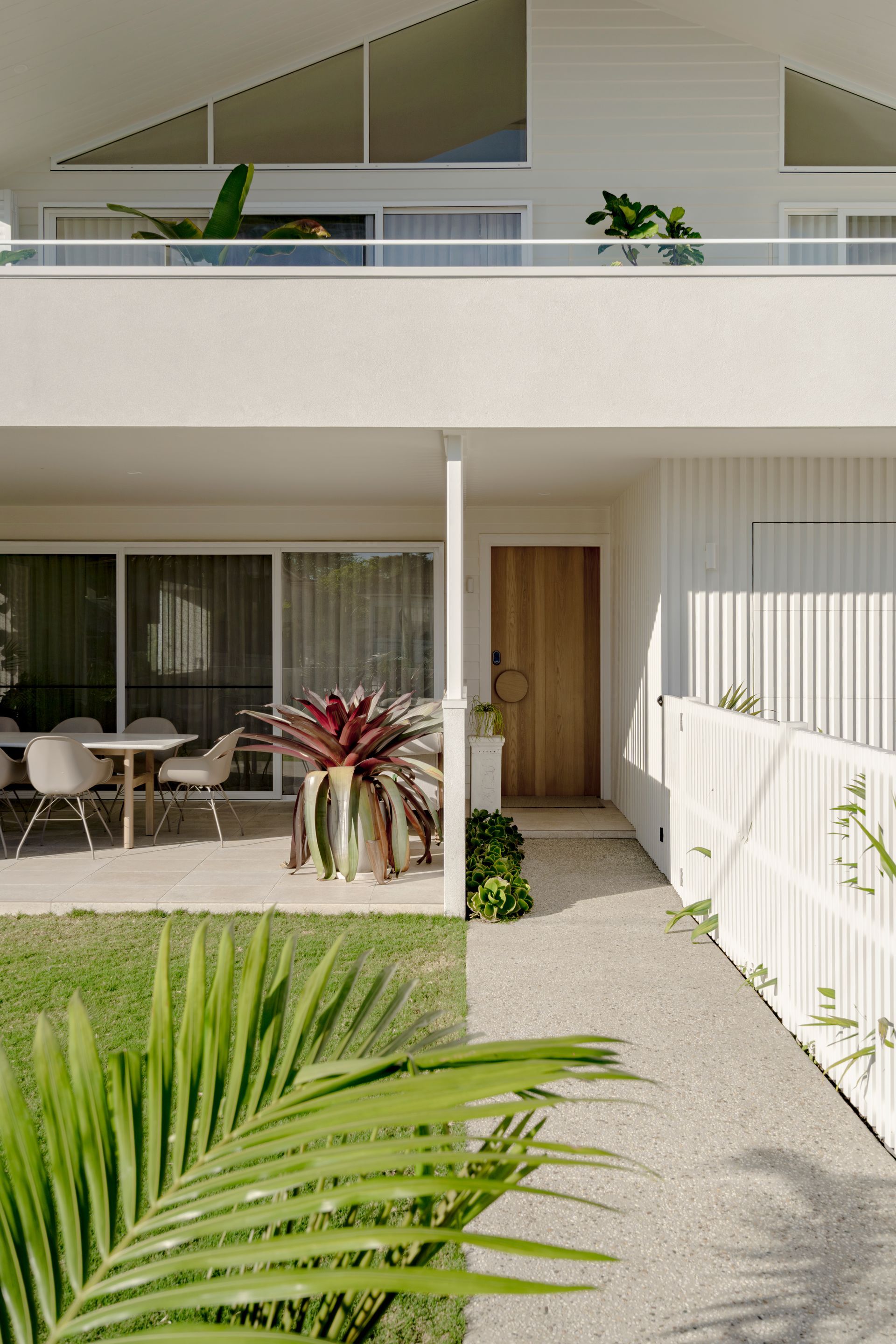 A white house with a balcony and a palm tree in front of it — DeBu Studios In Southern Sydney, NSW