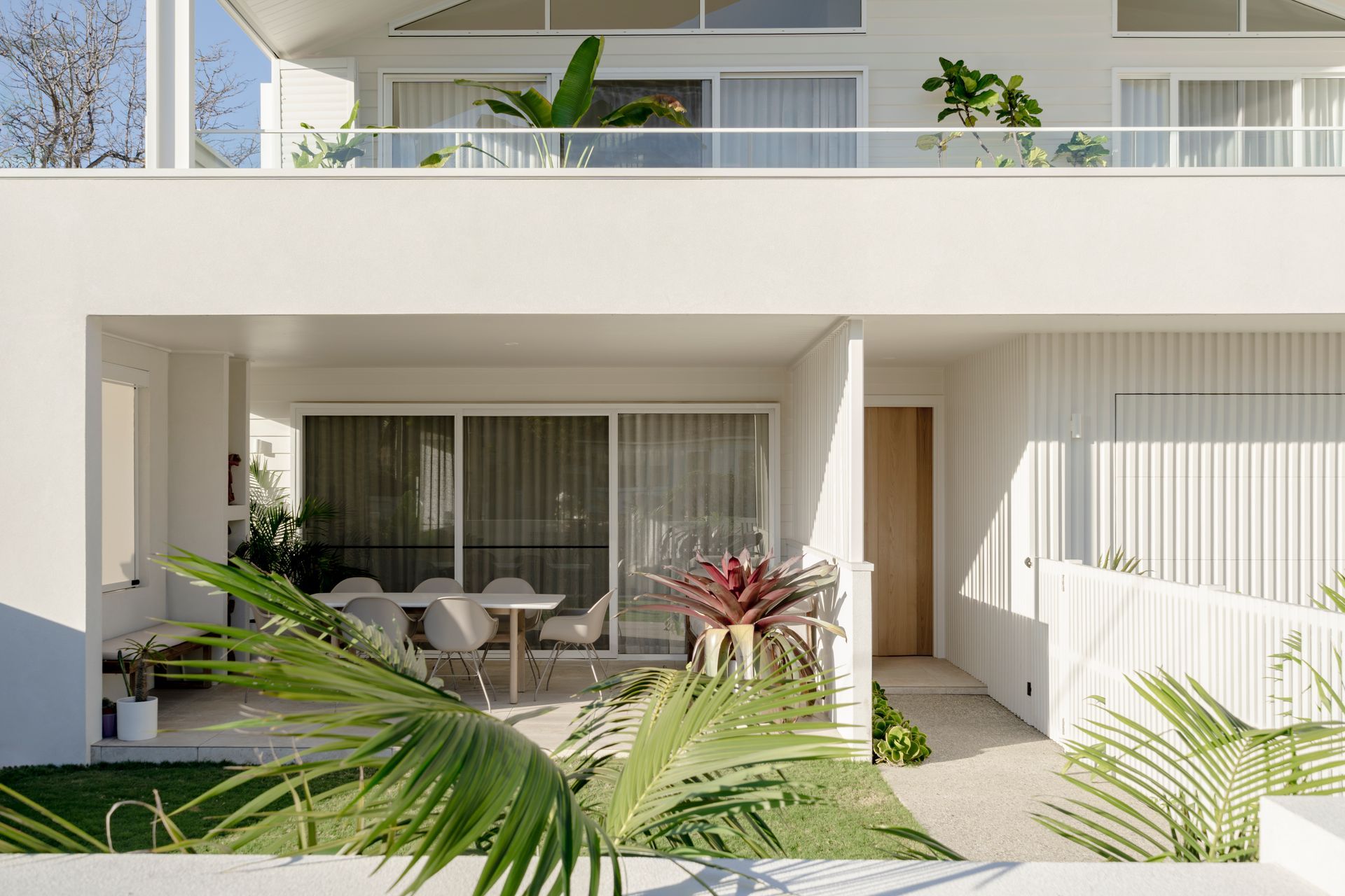 A white house with a balcony and a table and chairs on it — DeBu Studios In Southern Sydney, NSW