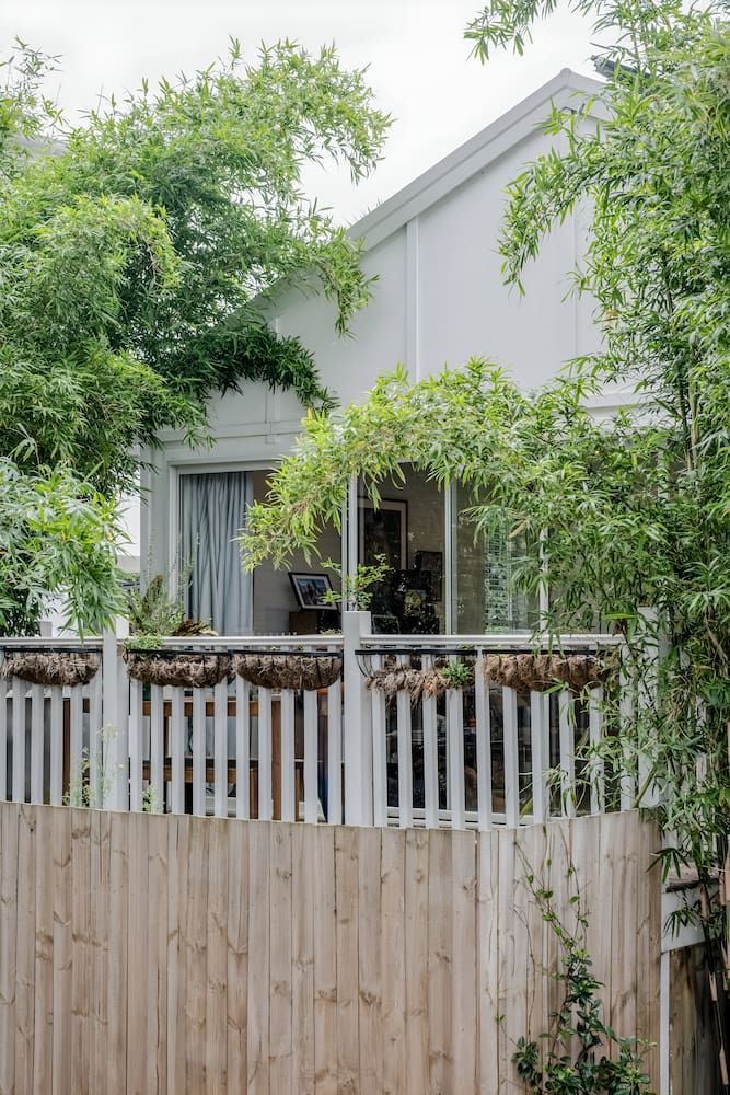 A White House With A Wooden Fence And Trees In Front Of It — DeBu Studios In Russell Vale, NSW