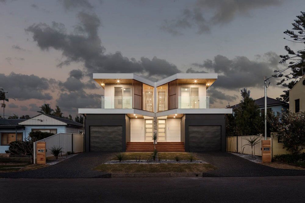 A Modern House With Two Garages is Lit Up at Night — DeBu Studios In Russell Vale, NSW