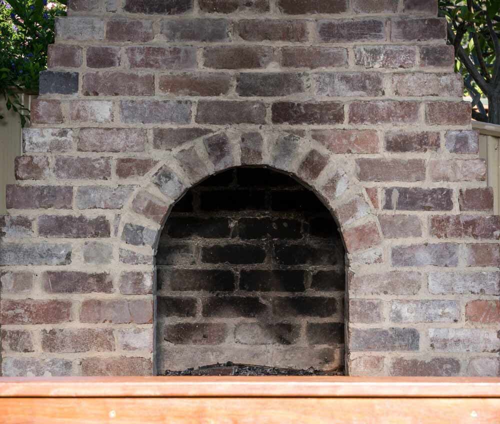A Brick Fireplace With a Wooden Bench in Front of It — DeBu Studios In Russell Vale, NSW