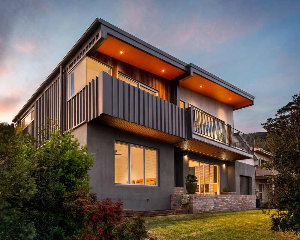 A Large House With a Balcony and a Lot of Windows is Sitting on Top of a Lush Green Hillside — DeBu Studios In Russell Vale, NSW