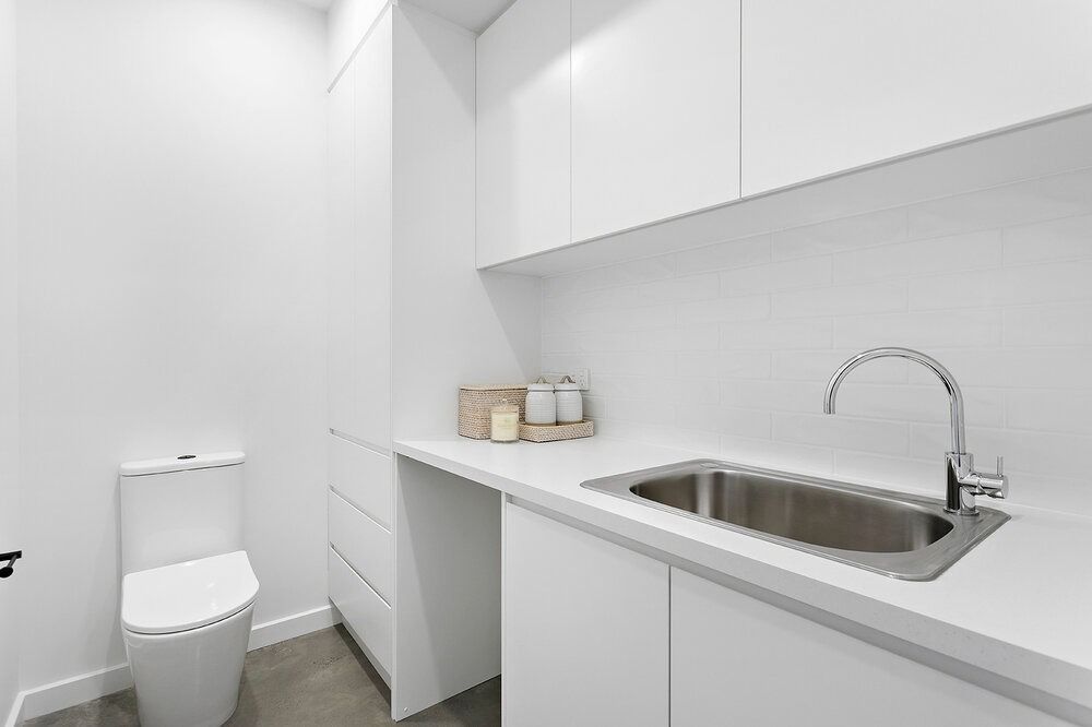 A Bathroom With a Sink, Toilet and White Cabinets — DeBu Studios In Russell Vale, NSW