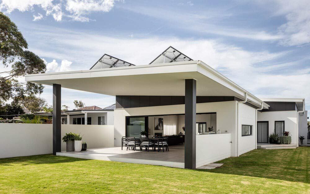 A White House With a Covered Patio and a Lawn in Front of It — DeBu Studios In Russell Vale, NSW