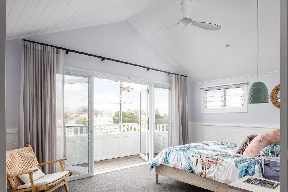 A Bedroom With a Bed, Chair and Sliding Glass Doors Leading to a Balcony — DeBu Studios In Russell Vale, NSW