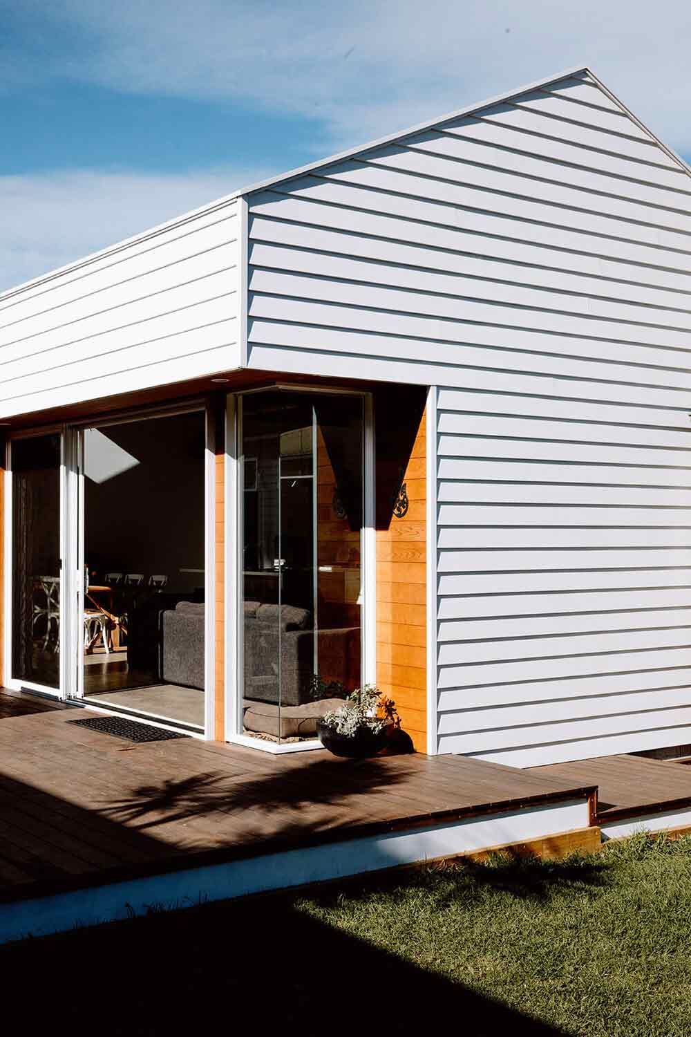 A Small White House With a Lot of Windows and a Wooden Deck — DeBu Studios In Russell Vale, NSW