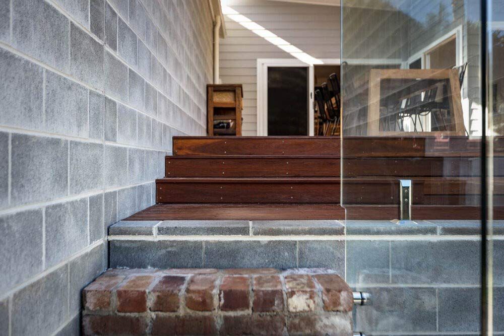 A Brick Wall With Wooden Steps Leading Up to a Deck — DeBu Studios In Russell Vale, NSW