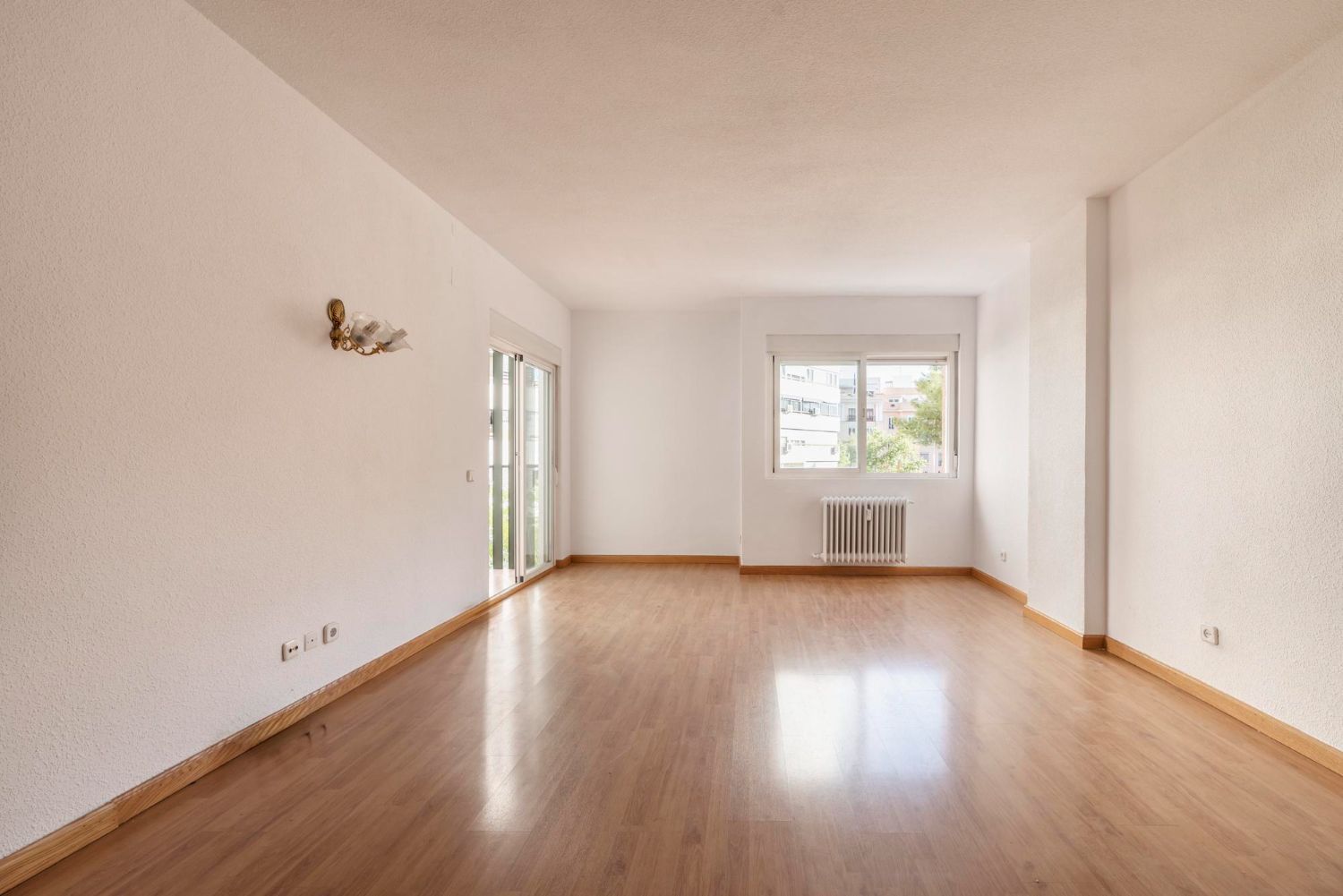 Person sweeping a wooden floor with a broom and dustpan.