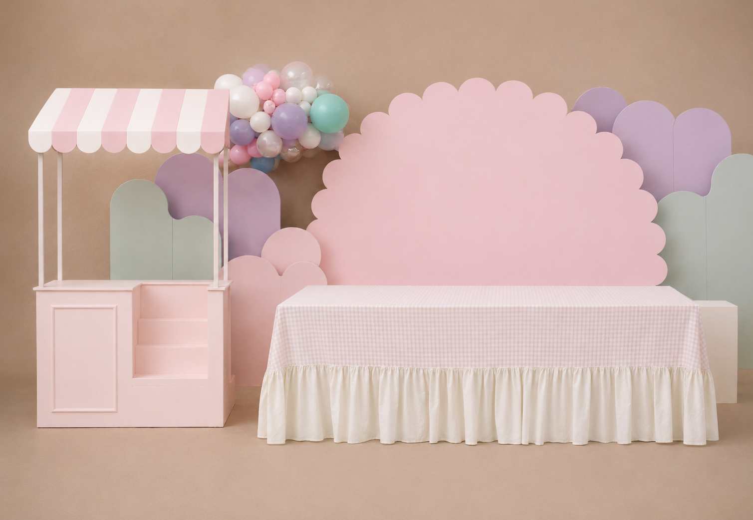 Carrinho de sobremesas rosa pastel e painel de fundo para o palco com balões e uma mesa coberta com tecido.