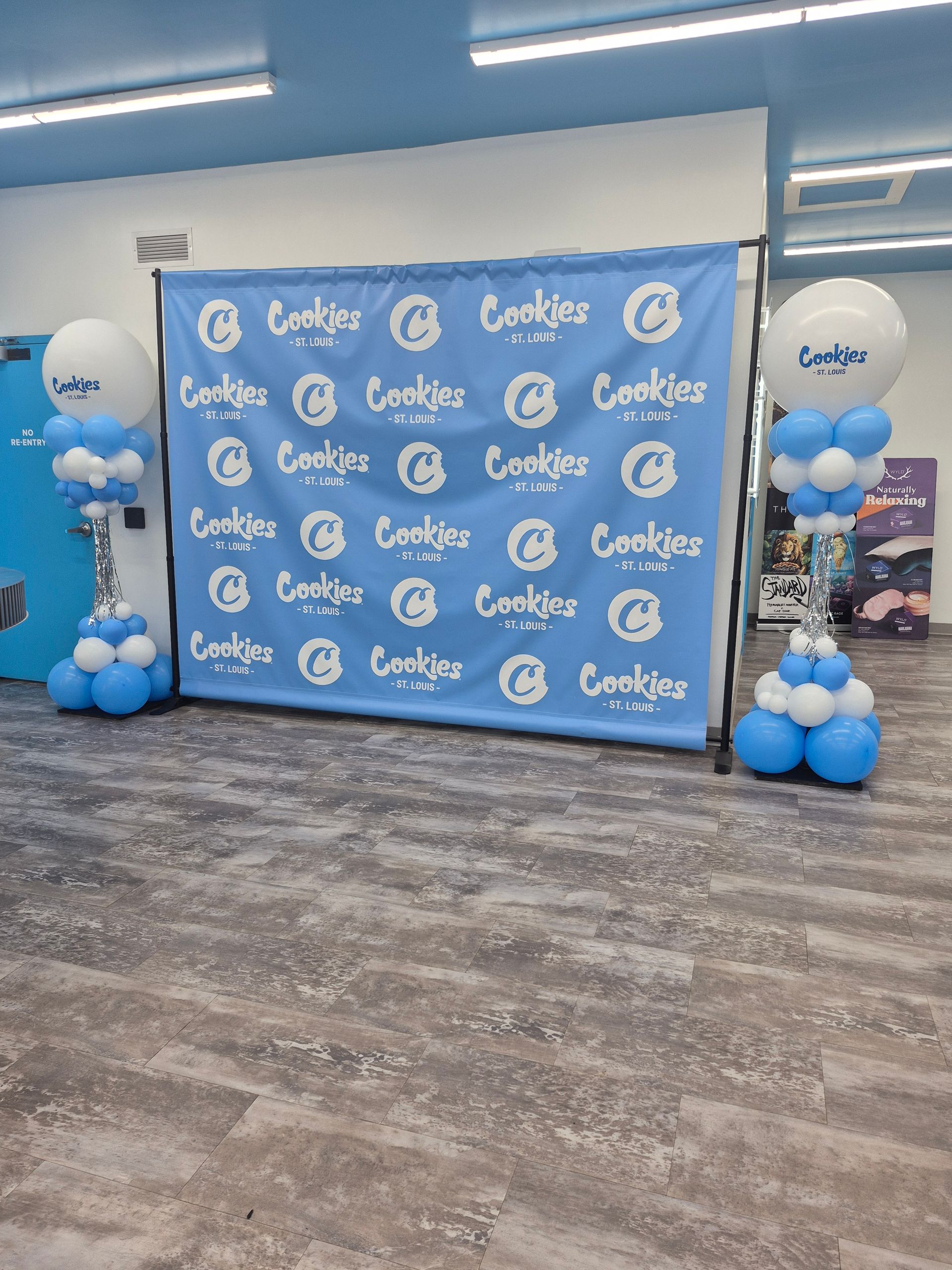 Cookies retail store opening event backdrop. Blue banner with logo, balloon decorations in blue/white.