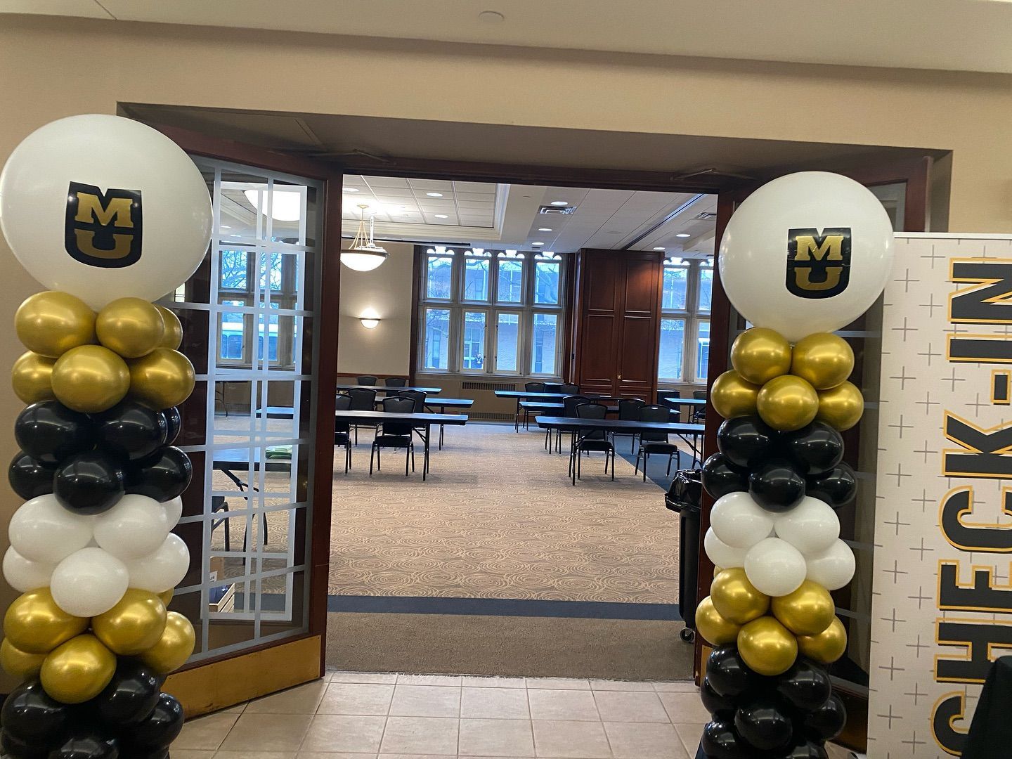 A room with balloons and a sign that says check in