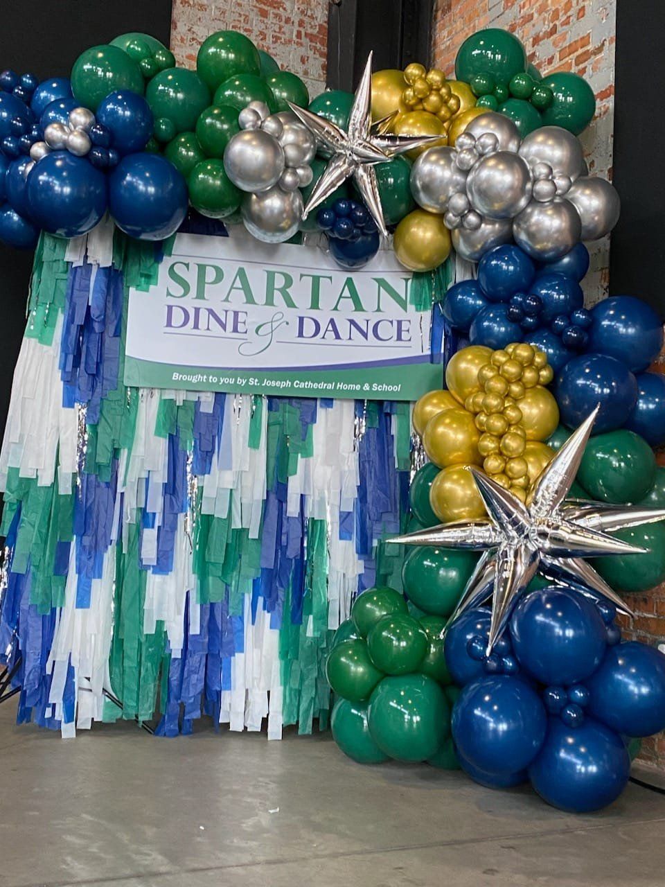 A sign that says spartan dine and dance is surrounded by balloons
