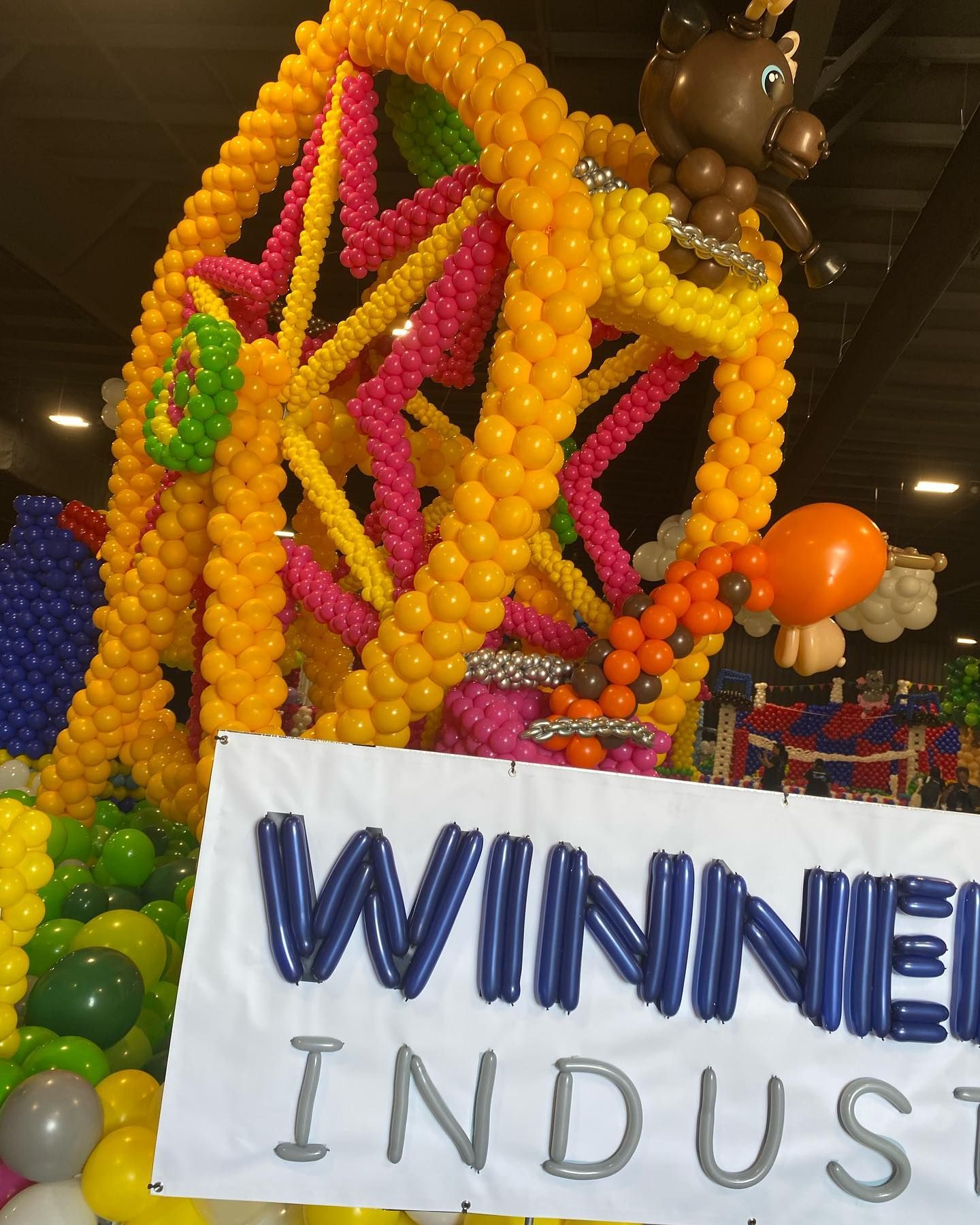 A ferris wheel made of balloons with a sign that says winner indust