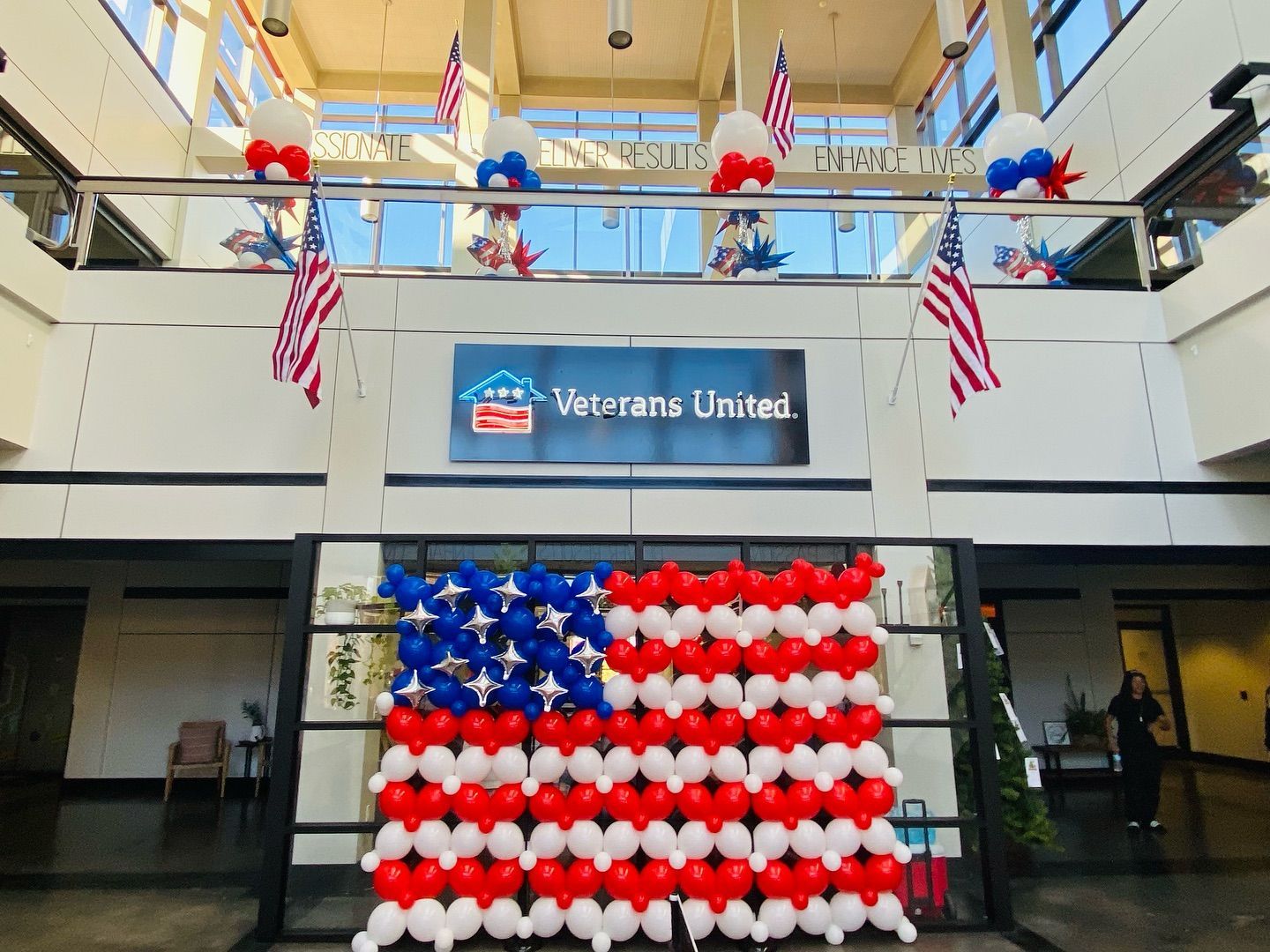 American flag made of balloons displayed indoors with Veterans United sign and flags.