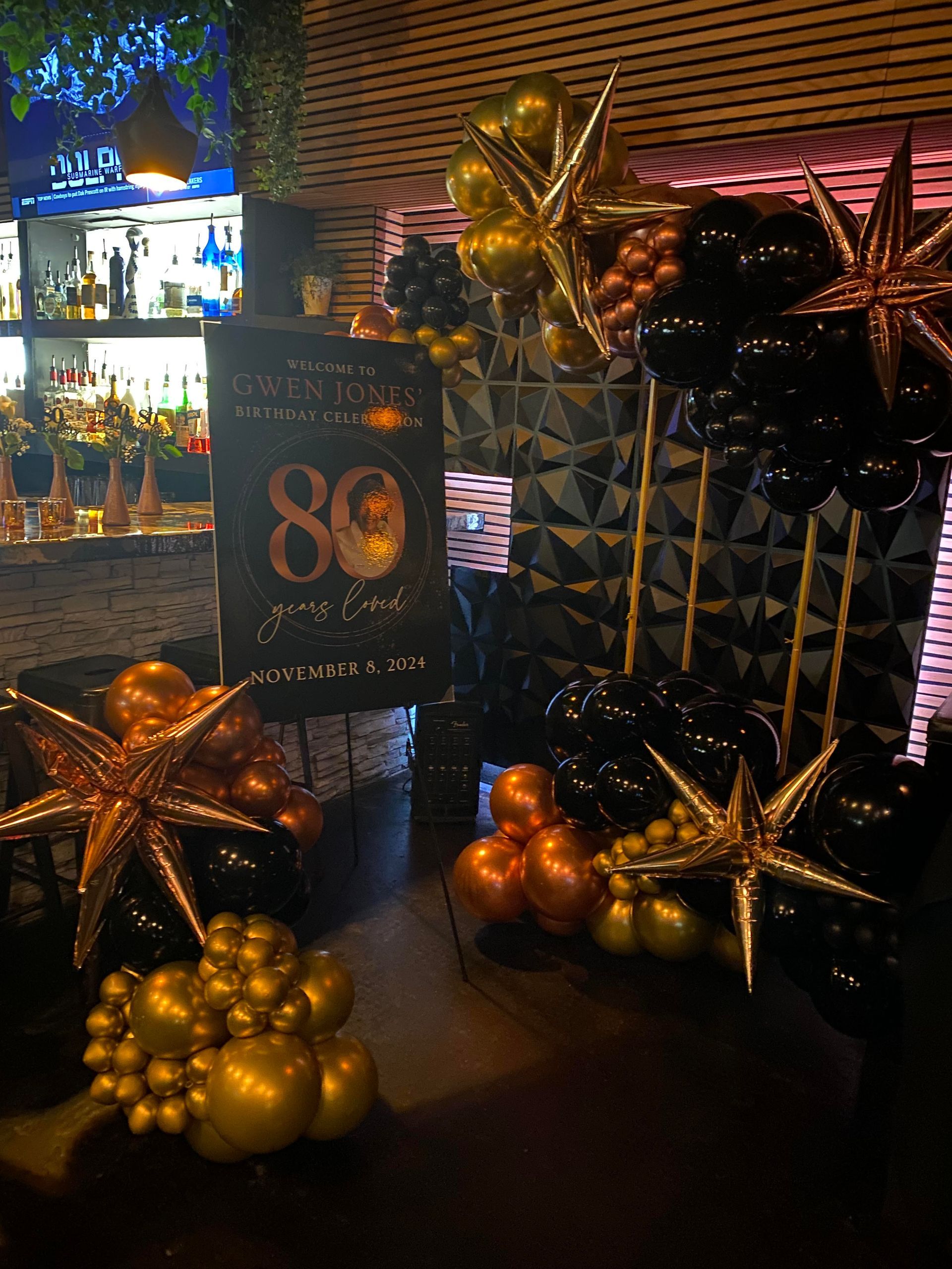 A room decorated with balloons and a sign that says 80