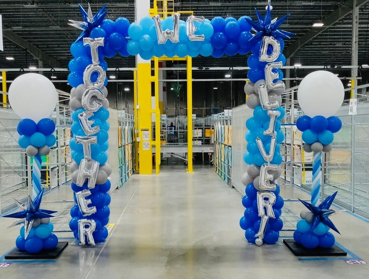 A blue and white balloon archway in a warehouse