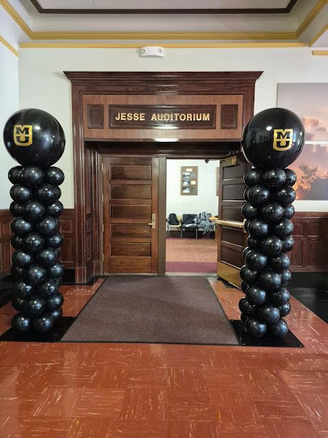 Black balloon columns with MU logo flank the entrance to Jesse Auditorium.
