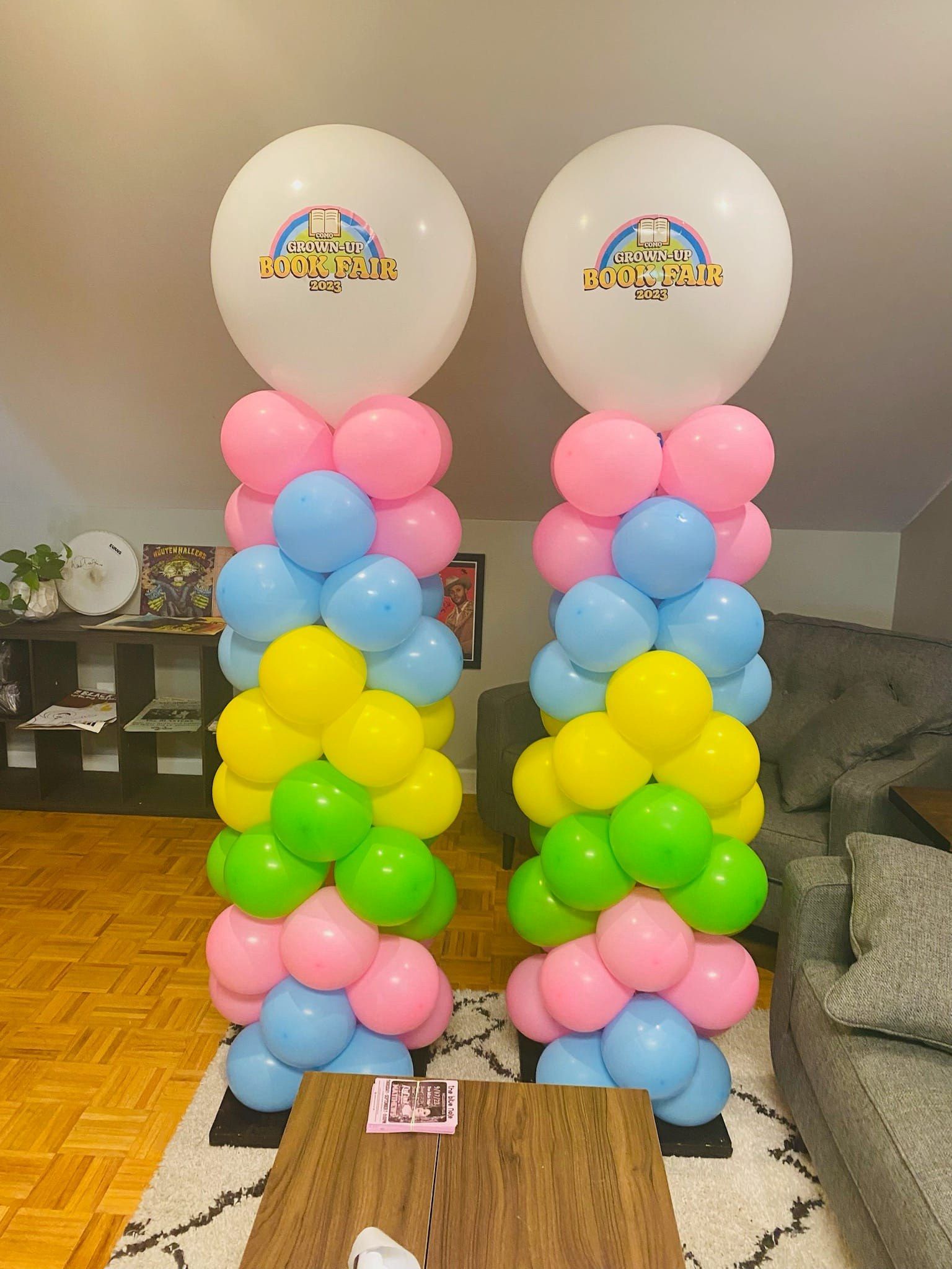 Two columns of balloons are sitting in a living room.