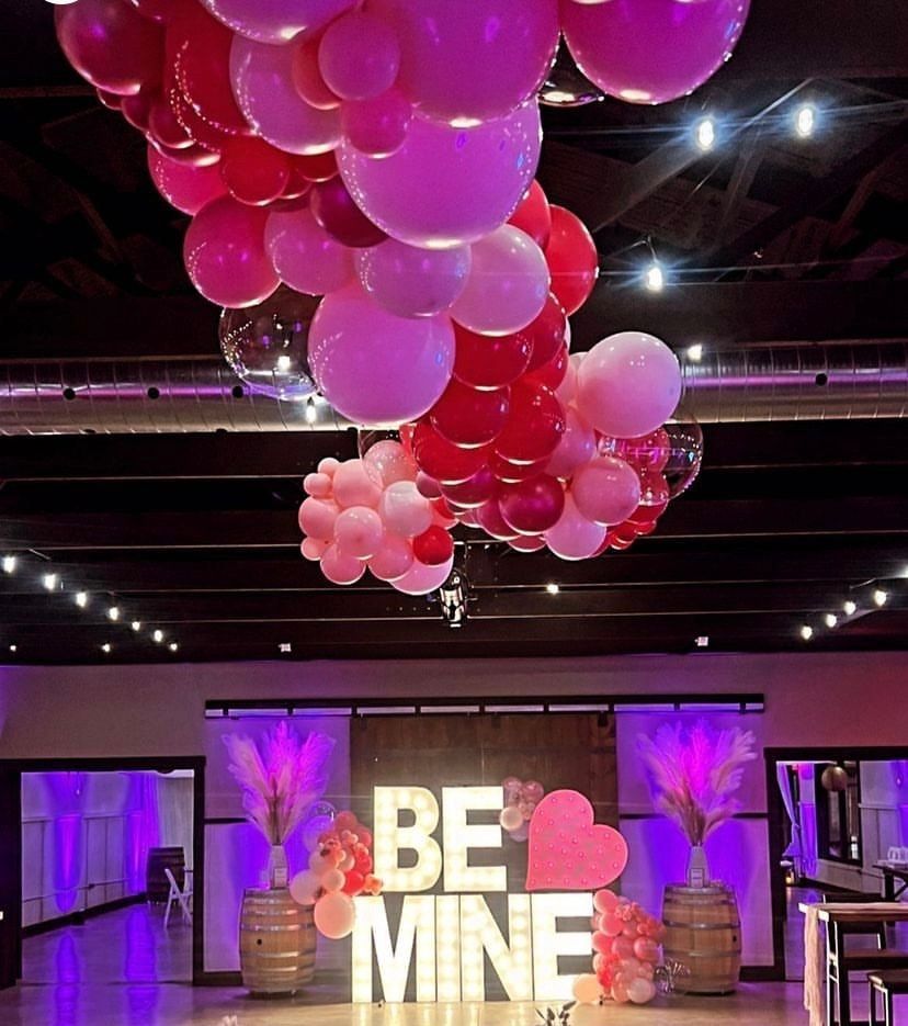 A room with balloons hanging from the ceiling and a sign that says be mine