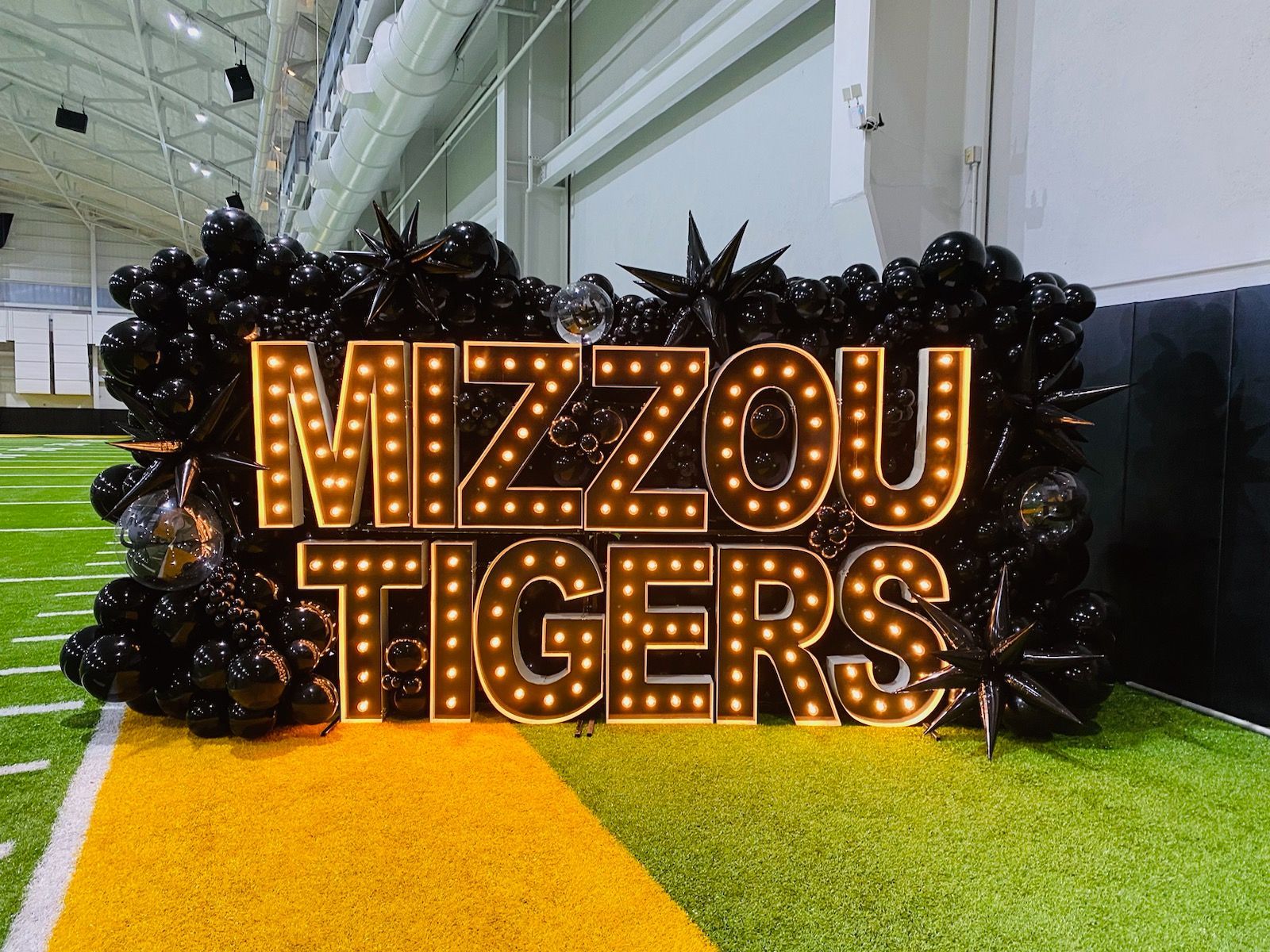 A sign that says mizzou tigers is surrounded by balloons
