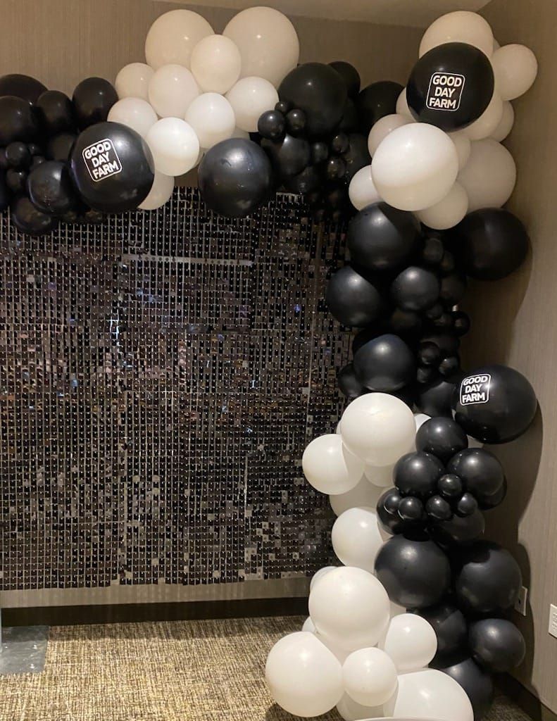 A bunch of black and white balloons are hanging on a wall.