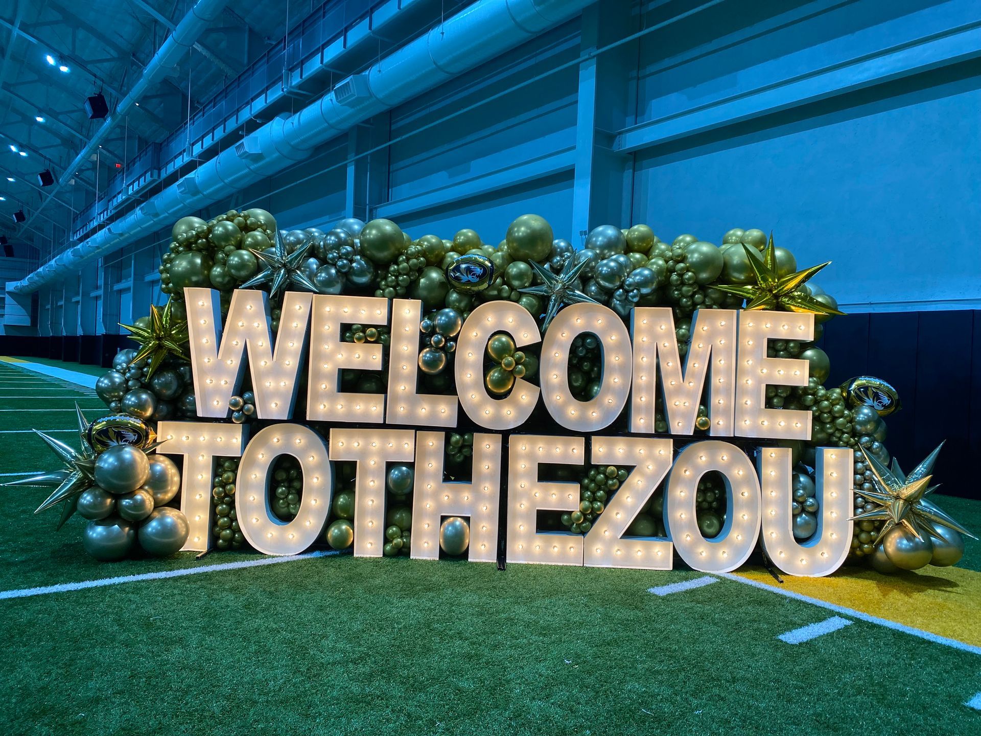 A sign that says `` welcome to thezou '' is sitting on top of a football field.