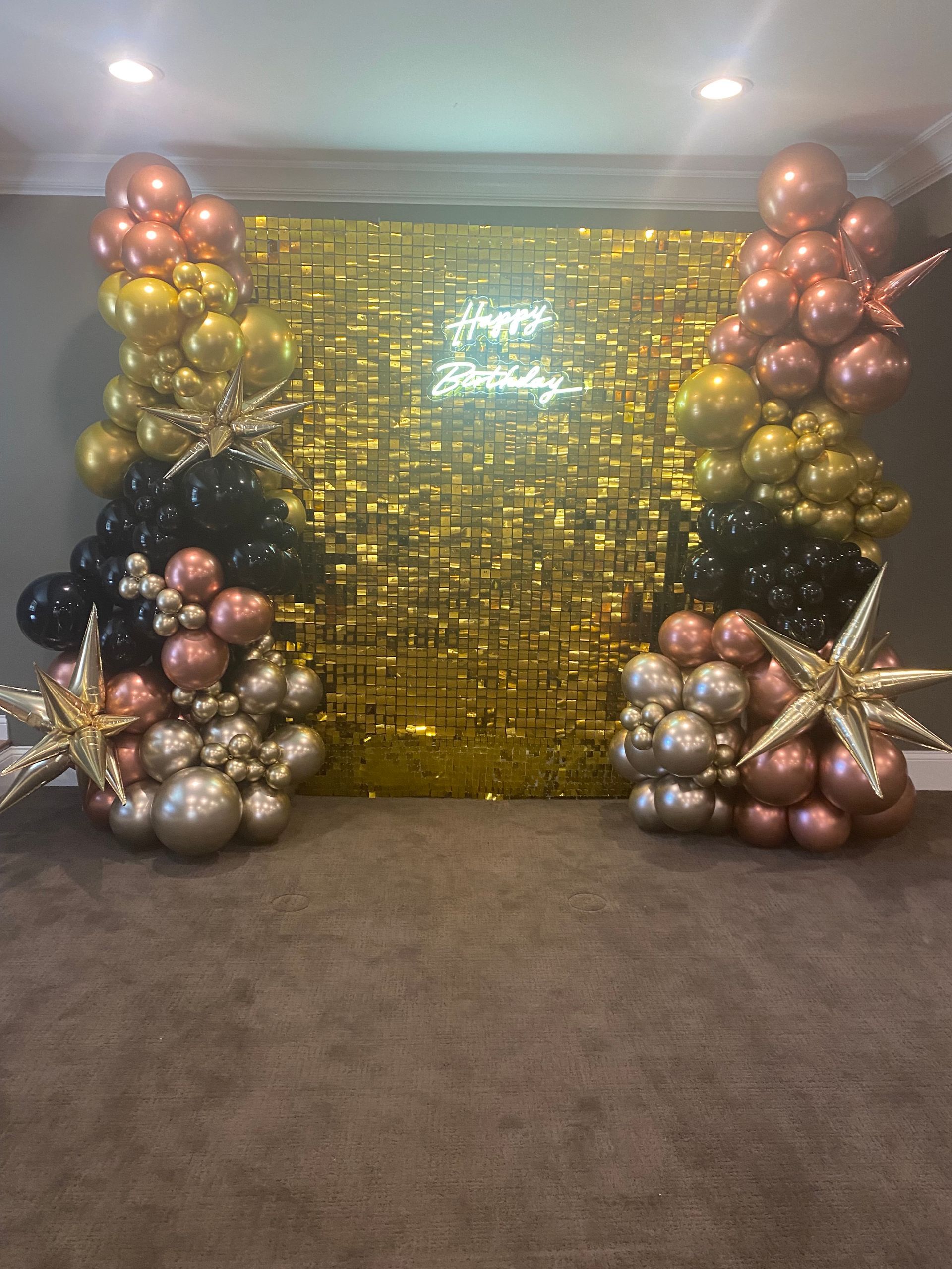 A room filled with balloons and a gold wall.