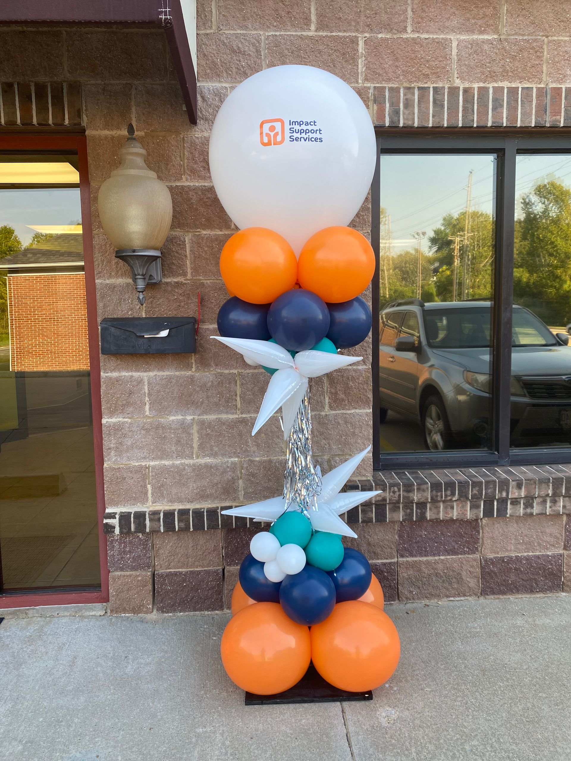 A bunch of balloons are stacked on top of each other in front of a building