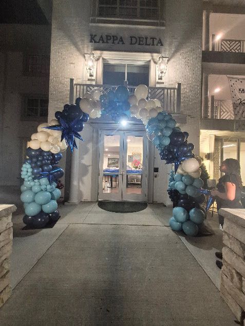 Entrance to a Kappa Delta sorority house decorated with blue and white balloon arch.