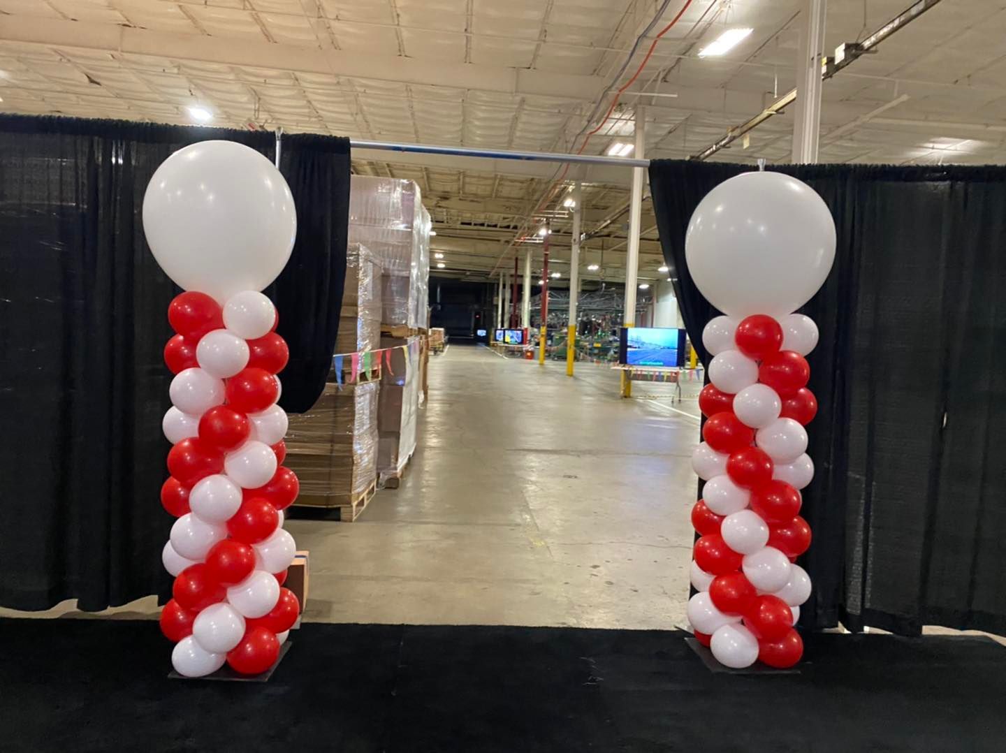 Two red and white balloon columns in a warehouse.