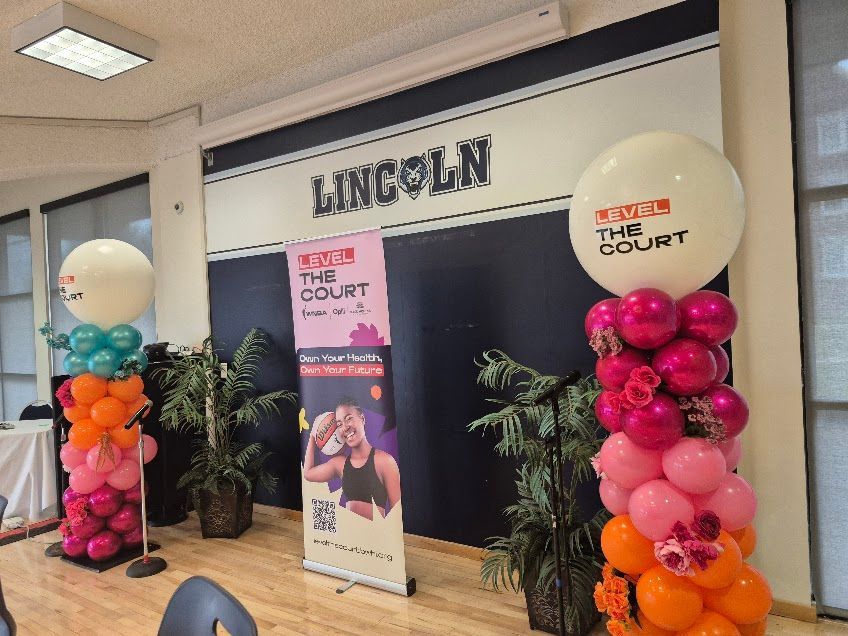 Event setup with balloon columns in front of a backdrop that says