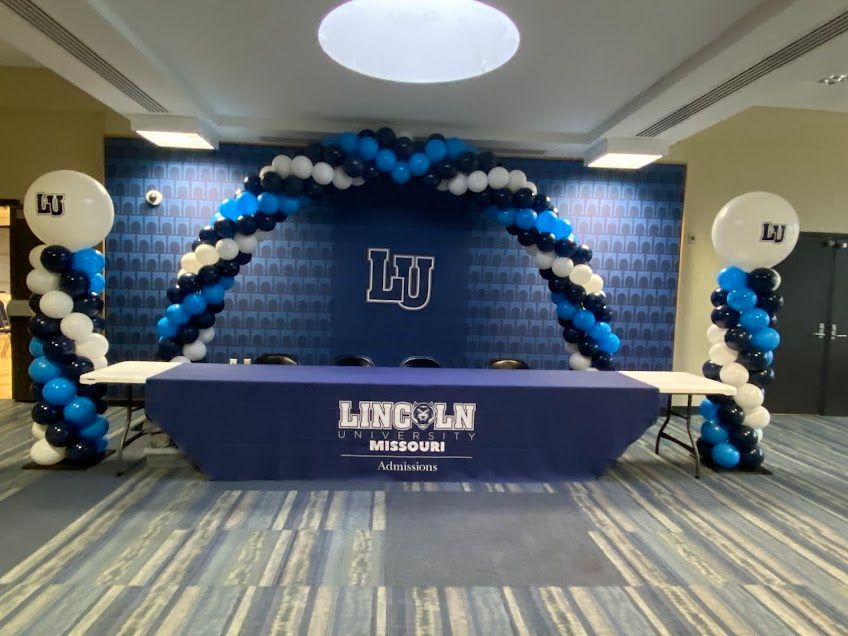Lincoln University signing event backdrop with balloons and table.
