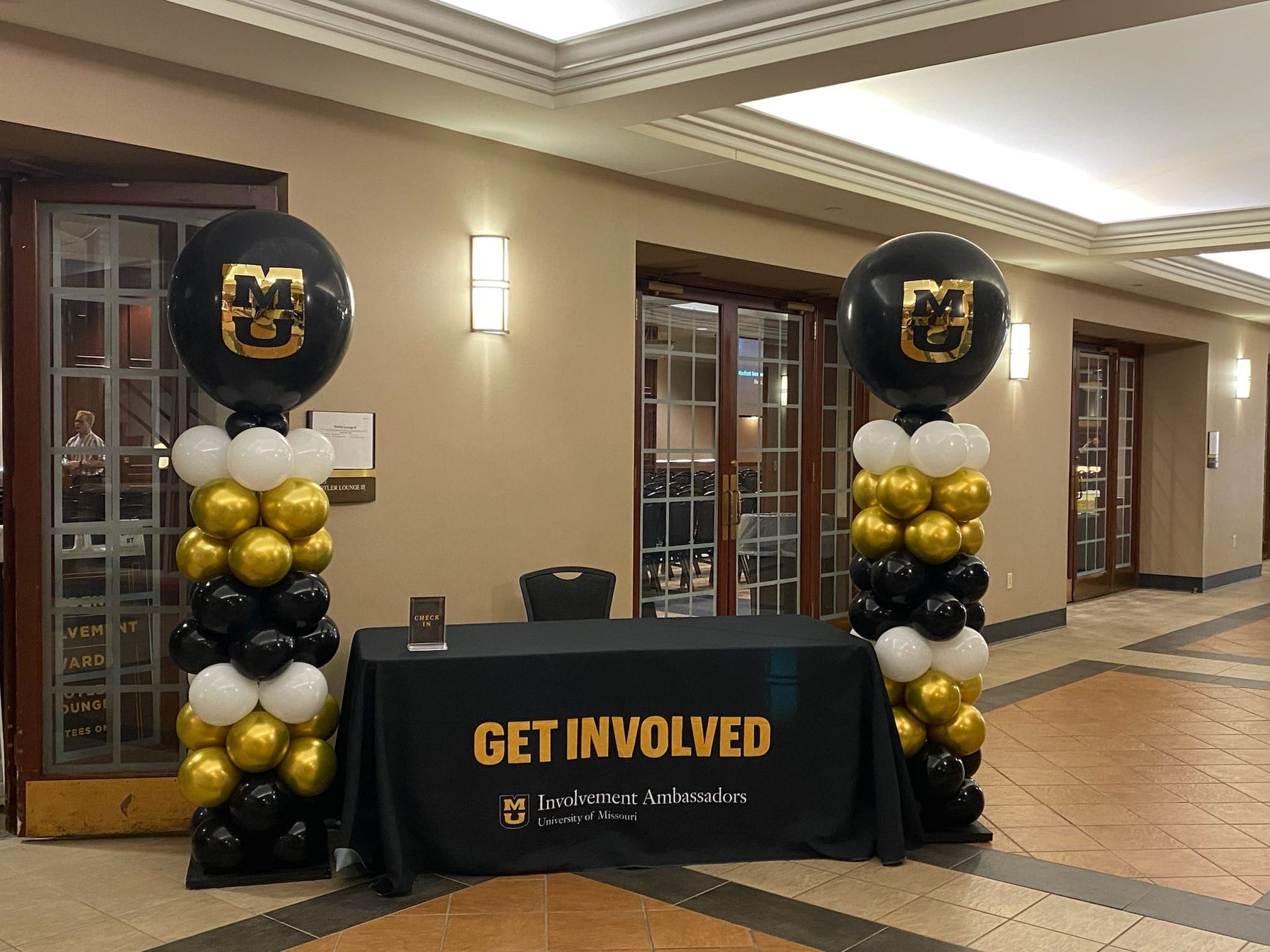 A table with a get involved sign on it is surrounded by balloons.